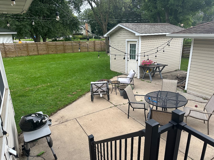 Large fenced backyard with patio furniture and electric grill available for use.