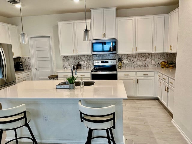 large bright kitchen with accents of silver and gold, breakfast bar/work station with two USB plugs, pin lights, and 2 comfy barstools - Fully stocked kitchen!