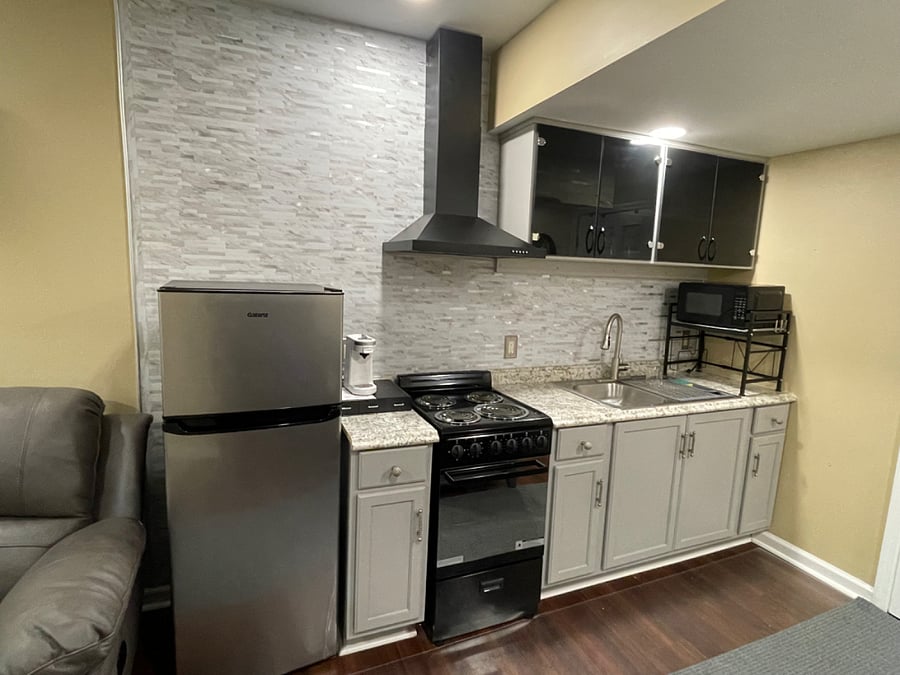 Kitchen area equipped with dishes, glasses, pots & pans, cooking utensils.