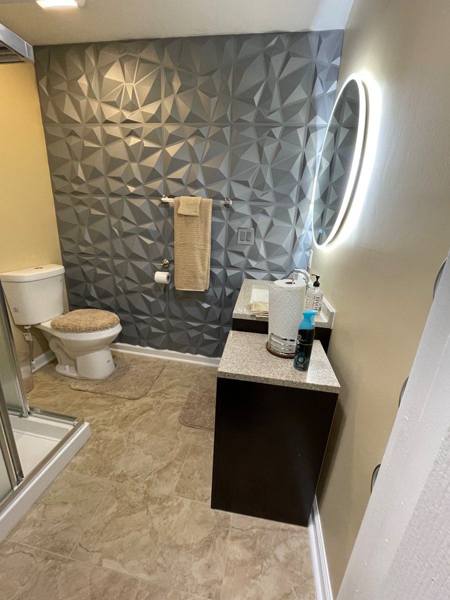 Ceramic tile bathroom with tiled shower, accented wall, round LED mirror with Bluetooth. Vanity with storage cabinets & drawers.