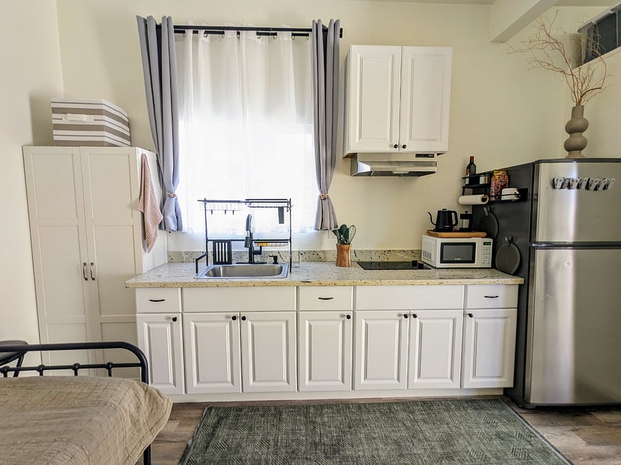Fully stocked kitchen with two burner electric stove & fan, coffee/tea bar, full size sink & fridge