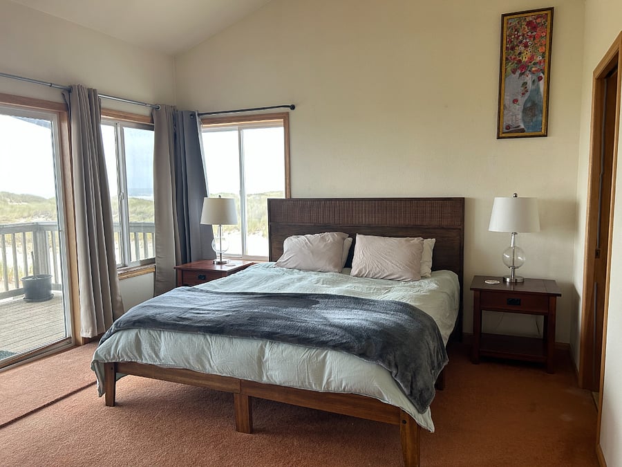 Spacious primary bedroom with king bed, adjoining bathroom, balcony access, and ocean views