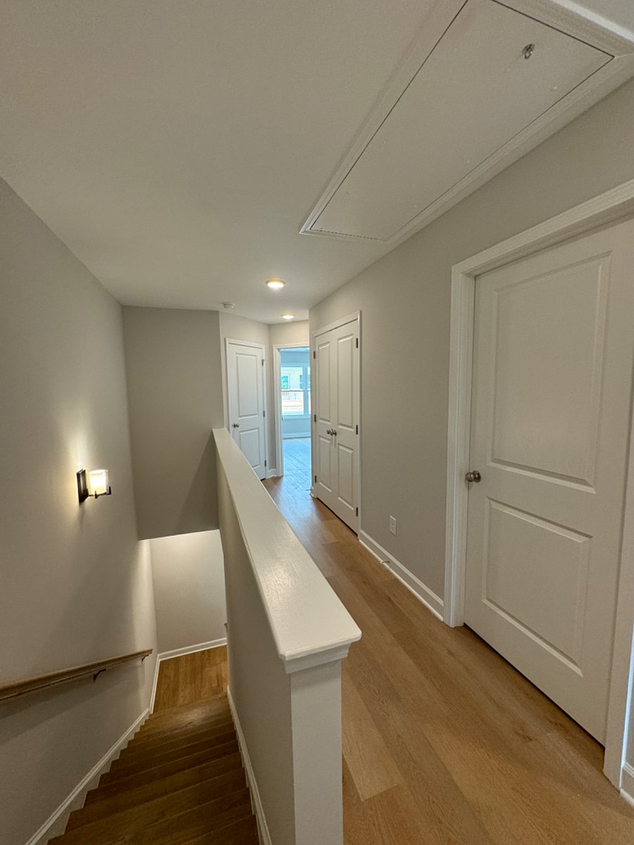 Upstairs hallway. First door is walk in laundry room with washer/dryer. Second door is linen closet with shelving. Corner door is utility closet.