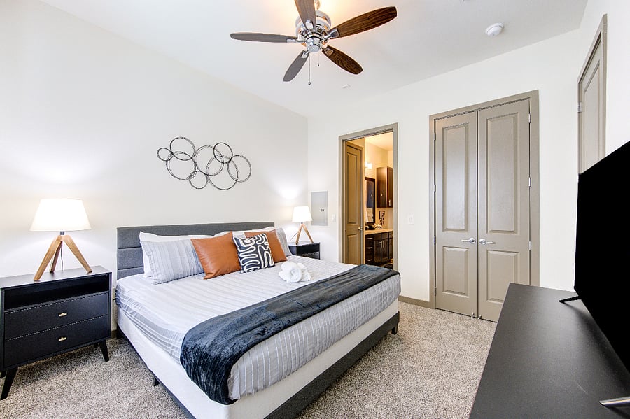 Bedroom with walk-in closet, 43" smart TV, storage and adjacent bathroom ensuite.