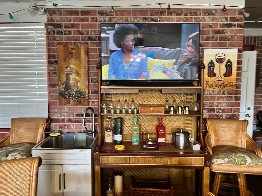 Enclosed patio with large screen television and bar area