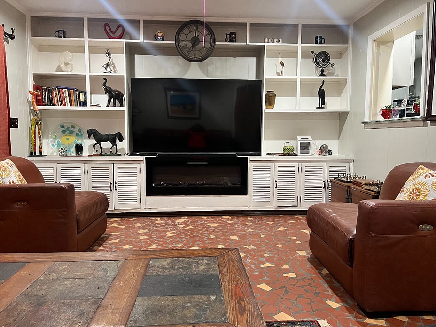 Television room with large screen television and library shelving.