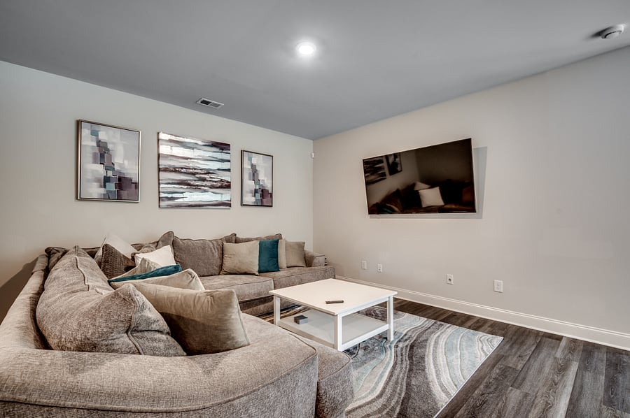 Cozy L-shaped sofa perfect for lounging, paired with a wall-mounted smart TV and a chic coffee table in the main floor living area.