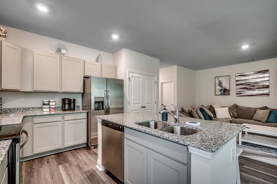 Spacious kitchen island with a sink, garbage disposal, dishwasher, and a fridge featuring filtered water and a convenient door ice dispenser.
