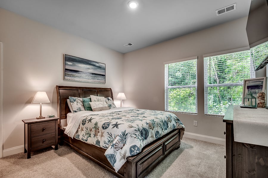 Master bedroom retreat with a cozy queen bed, ocean-inspired decor, a spacious dresser, and a large wall-mounted smart TV for ultimate relaxation.