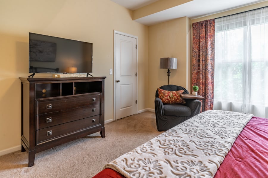 Master bedroom with a view of the Smart TV and the door of the walk in closet. 