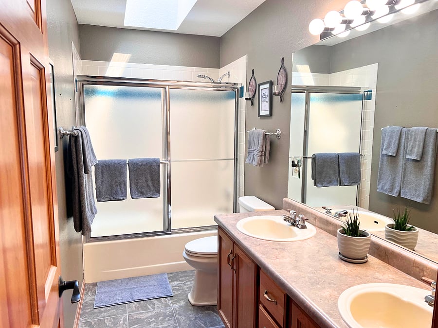 Bathroom with dual sinks and skylight.