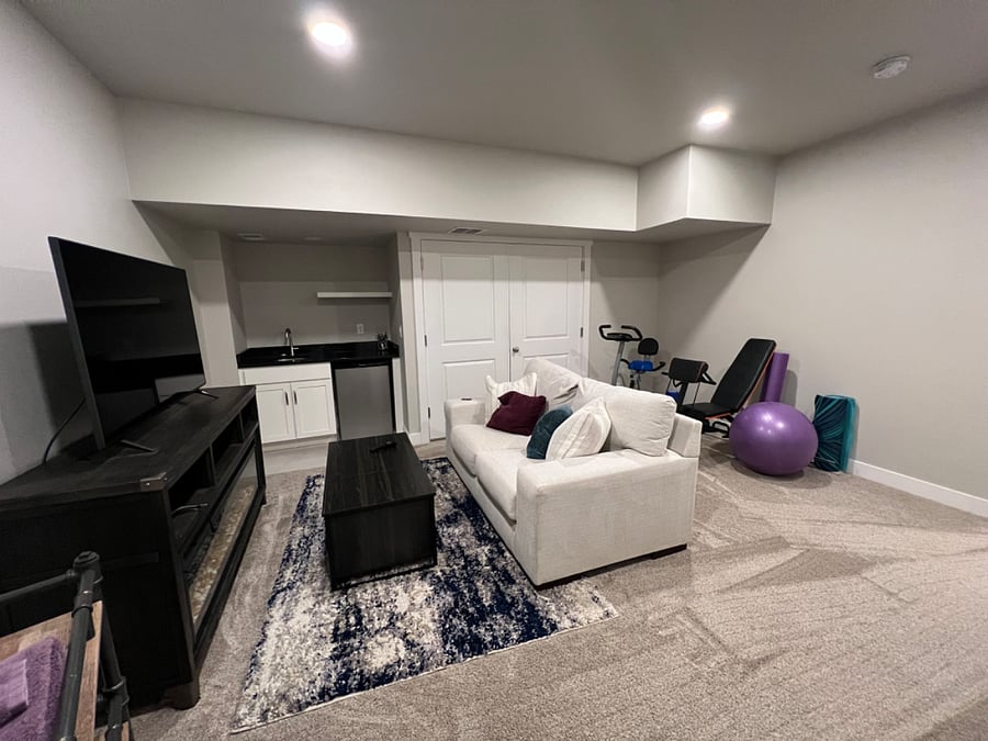 Private basement with 65 TV, wet bar, and exercise equipment. Basement also boasts a full bath, bedroom, and storage.