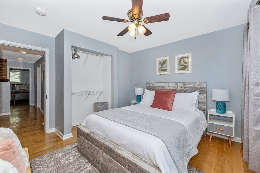 Second bedroom with queen size bed, blackout curtains, under bed storage, and ironing board.