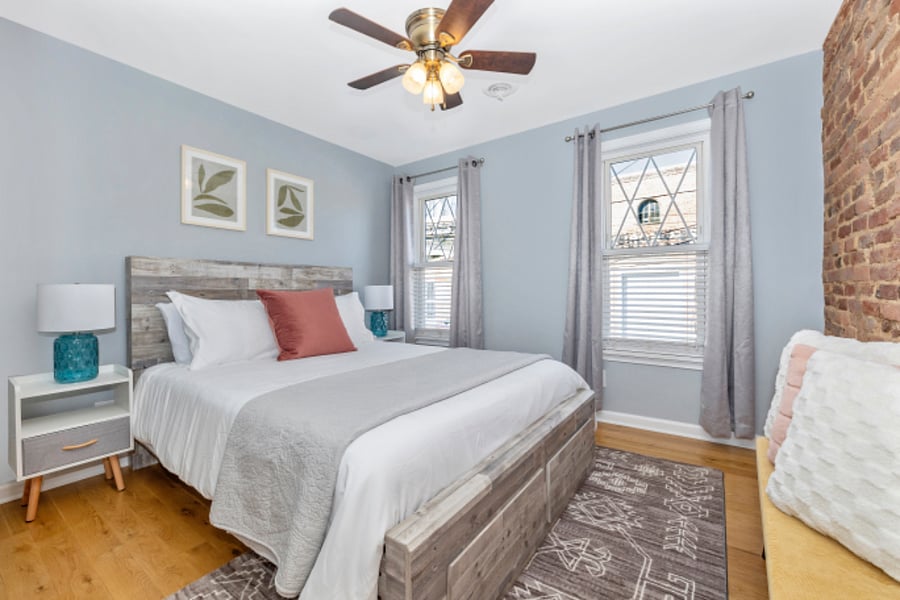 Second bedroom with queen size bed, blackout curtains, under bed storage, and ironing board.