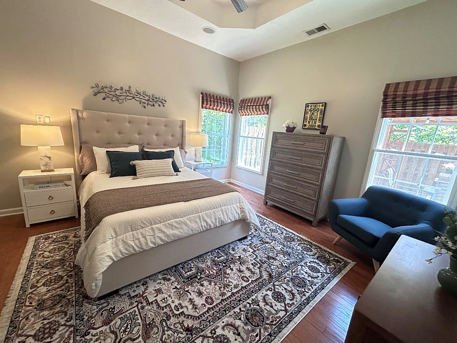 Primary bedroom downstairs with tray ceiling, Roman shades, walk-in custom closet, ensuite bathroom. Windows face hillside (no neighbors) and back patio for total privacy.