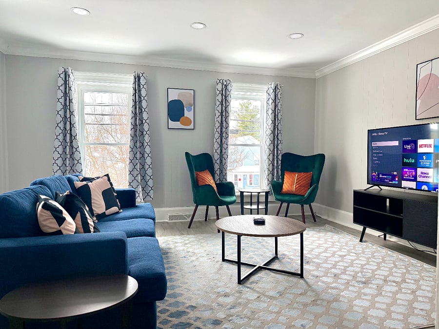 Relax in this cozy and stylish living room featuring a deep, large comfortable sofa and two chic accent chairs, perfect for sipping coffee and reading while enjoying the view through the window. A good-sized smart TV is also available for your entertainment.