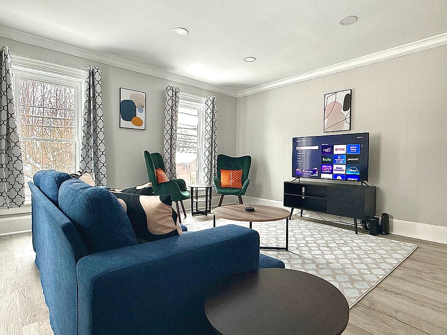 This inviting living room is the perfect blend of comfort and style, featuring a large, deep sofa and two chic accent chairs. With plenty of natural light, it creates a bright and airy space ideal for relaxing, reading, or enjoying your favorite shows on the smart TV.
