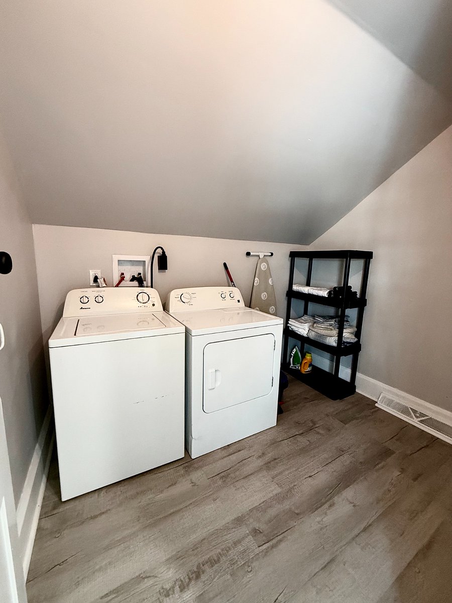 The spacious private laundry room features a washer and dryer, ample storage options, and an ironing board with an iron, providing everything you need for a convenient laundry experience.