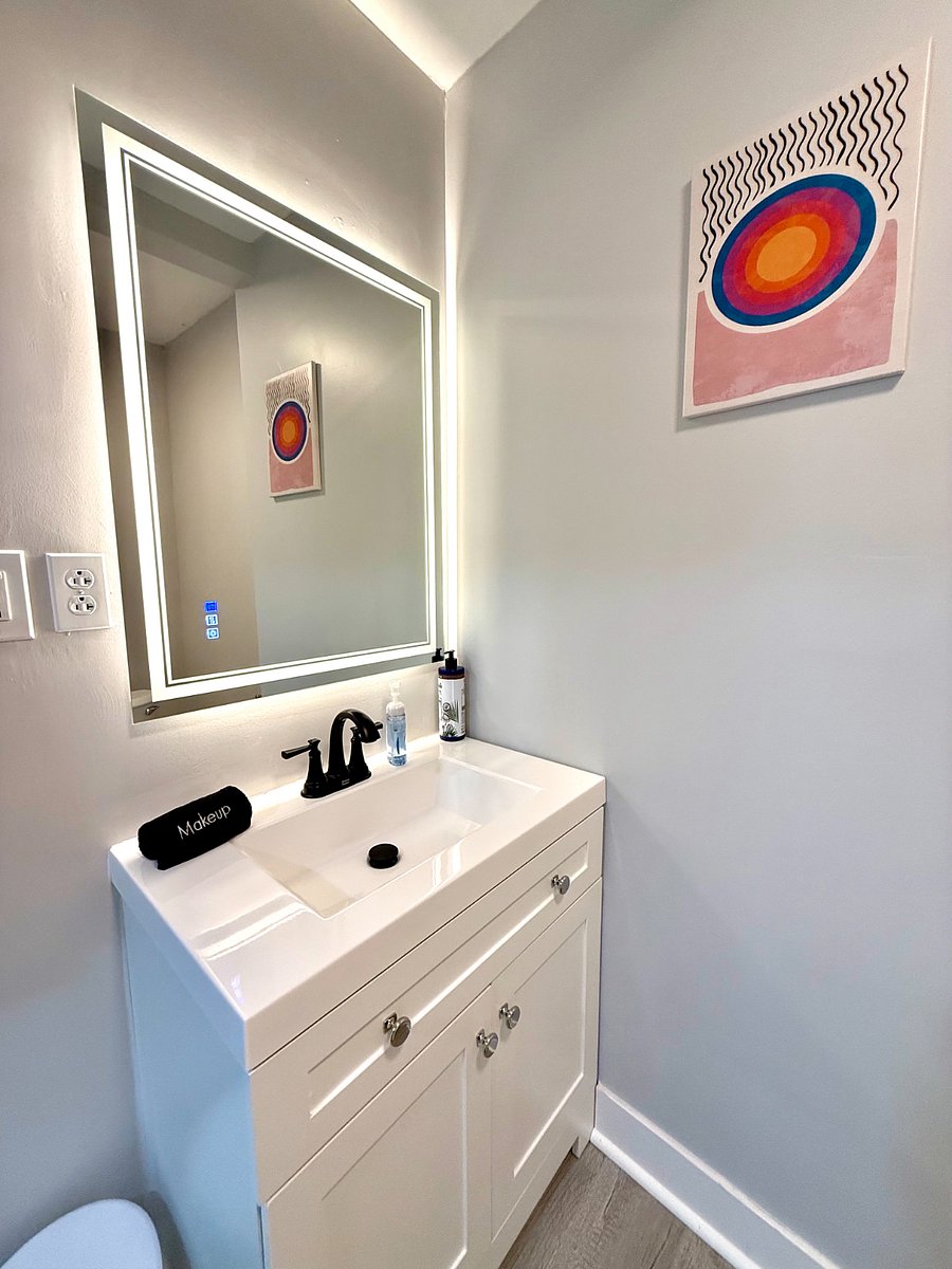 The bathroom features a beautiful modern mirror with amazing backlighting, along with various lighting options to suit your needs. The vanity provides additional storage, making this space both functional and stylish.