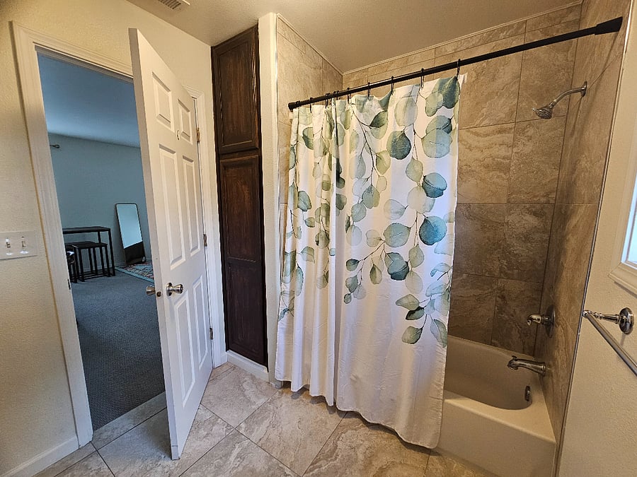 Private bathroom with a bathtub and storage.
