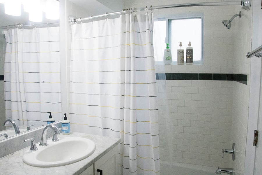 Bathroom with tub/shower combo with white/gray subway tile.
