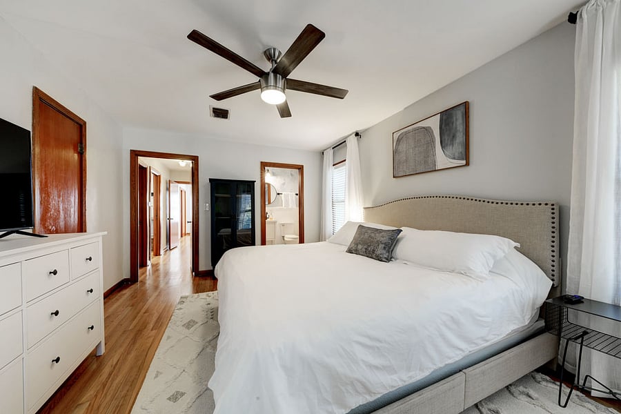 Primary bedroom facing bathroom - nice large bright space w/ white duvet and King bed