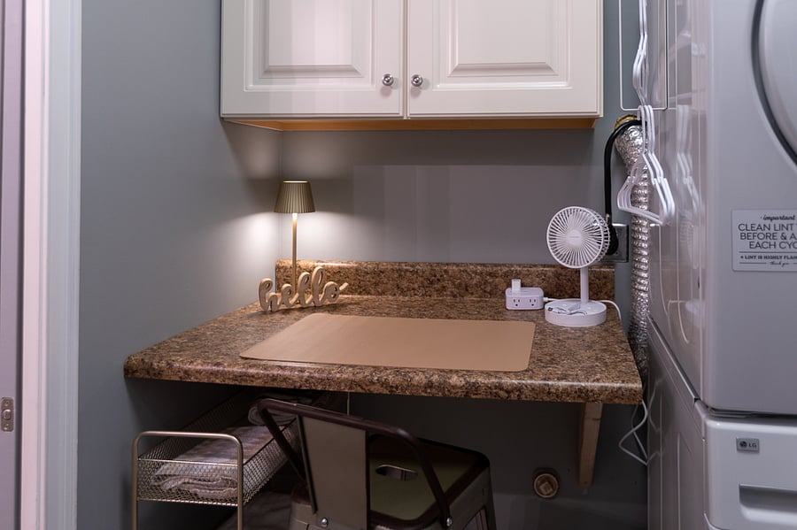 Desk workspace in laundry area. Light and portable fan. Charging station.