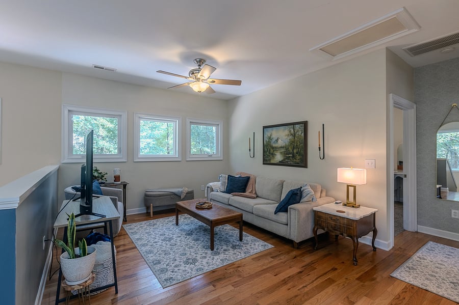 Living area. Open floor plan. Crank open windows to enjoy the cooler weather. This couch is long enough to accommodate an additional guest overnight. Touch lamp w/charging station. Extra outlet cube on end table. Storage in end table drawers.