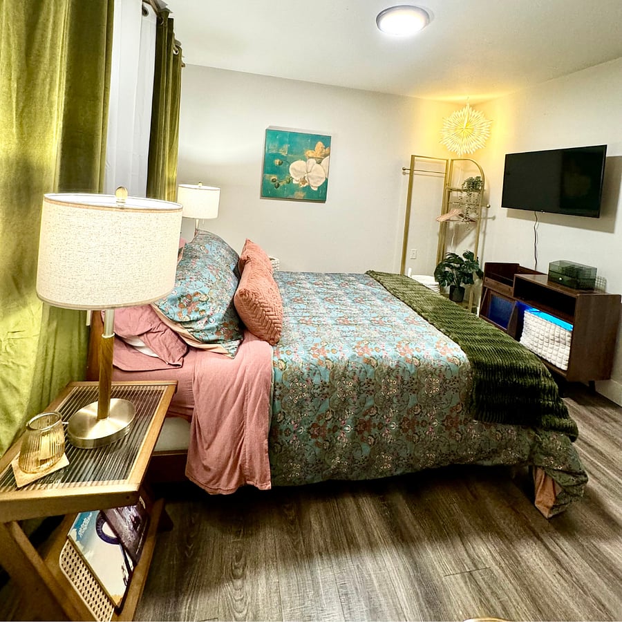 In addition to a closet for hanging clothes and built-in drawer system, you have a coat hanger for extra storage and media cabinet below your Smart TV to use for storage. You also have a shoe rack and laundry basket nestled in the corner. 