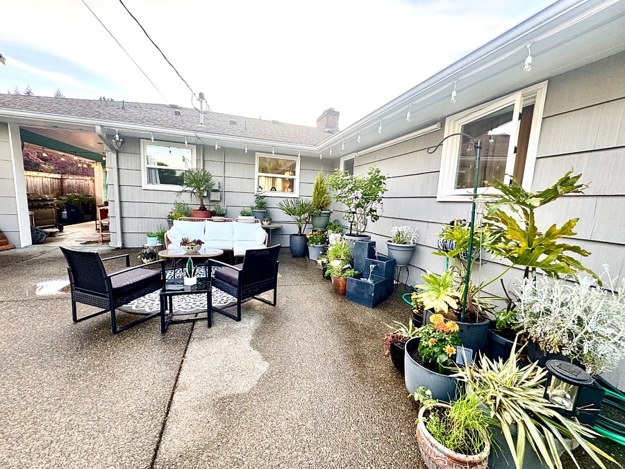 Covered year-round outdoor patio in Tacoma furnished housing  ideal for travel nurses, contractors, and professionals seeking flexible month-to-month living. Beautiful outdoor lounging sofa with chaise surrounded by native plants and fountain  relaxing furnished housing in Tacoma for healthcare professionals. 