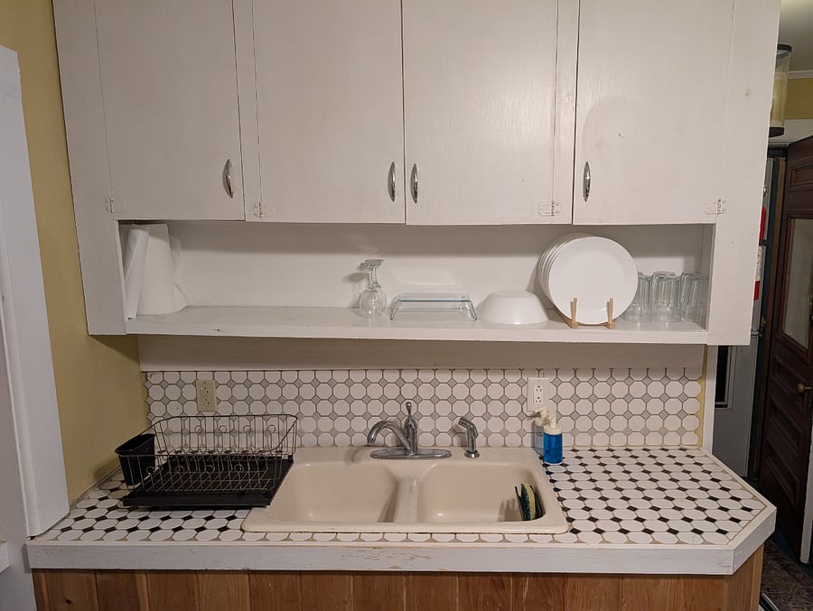 The kitchen has a farm-style double basin cast iron sink with good (albeit ugly) cabinet, counter, and overhead storage space. Dishes and utensils are provided (most of which are brand new).