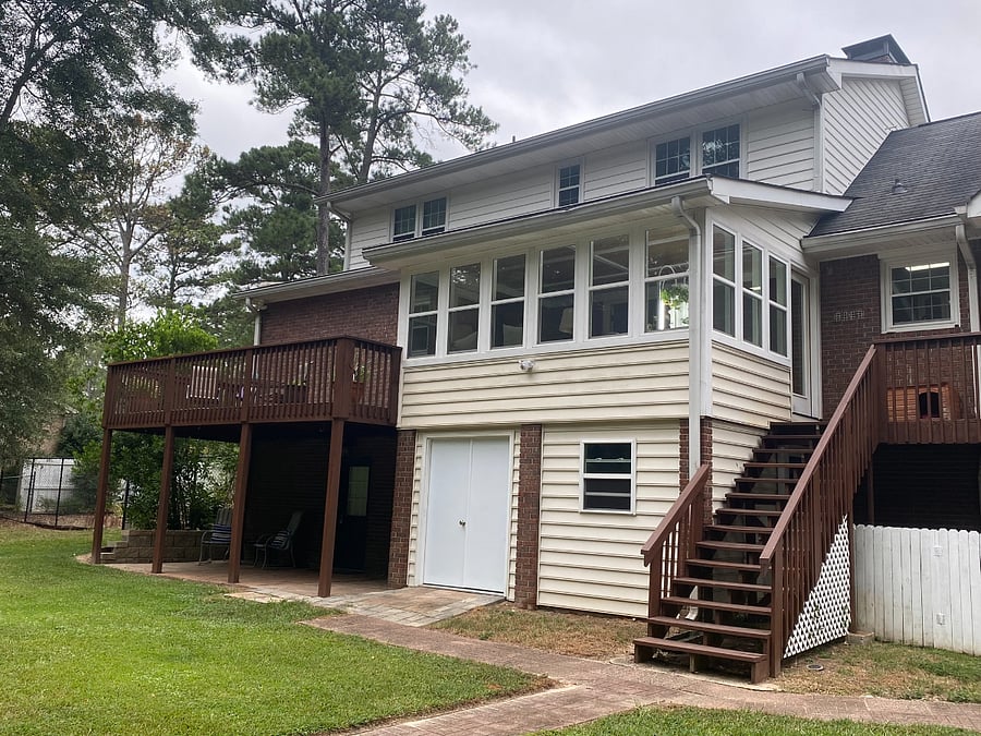 Exterior view of the shared sunroom and deck, with stairs down to the back yard and fire pit.