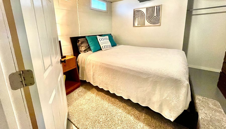 Basement Unit: Primary Bedroom with Queen Bed  Fresh linens, blackout curtains, and plenty of storage.