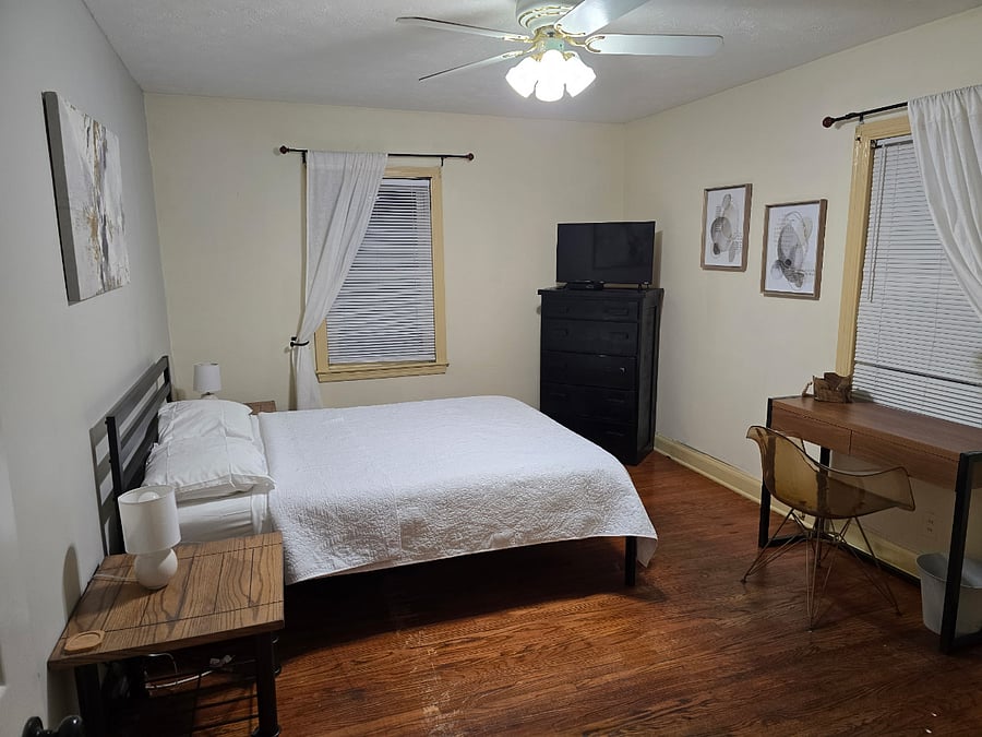 Bright and comfortable second bedroom featuring a queen-size bed, dedicated workspace, smart TV, and plenty of storageperfect for travel nurses or professionals seeking a quiet, fully furnished retreat