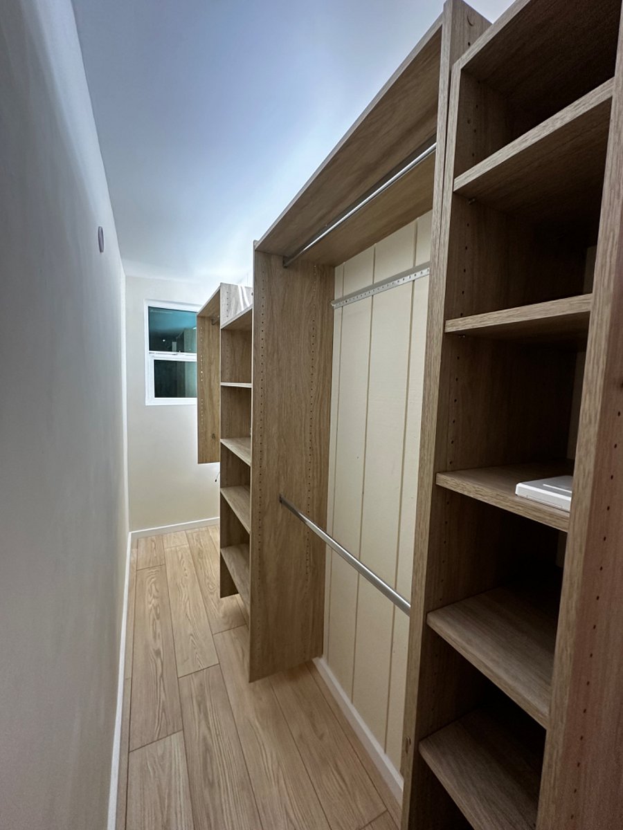 Large walk in wardrobe area includes plenty of space for hanging clothing, including shelves, a shoe rack as well as a dresser that was added after this picture was taken. The wardrobe unit has ample storage and is about 12 feet in length.