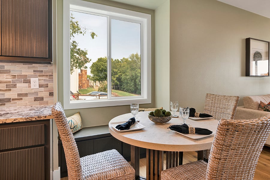 Modern dining area with comfortable chairs and window bench seating, set alongside large windows that enhance natural light and everyday comfort.