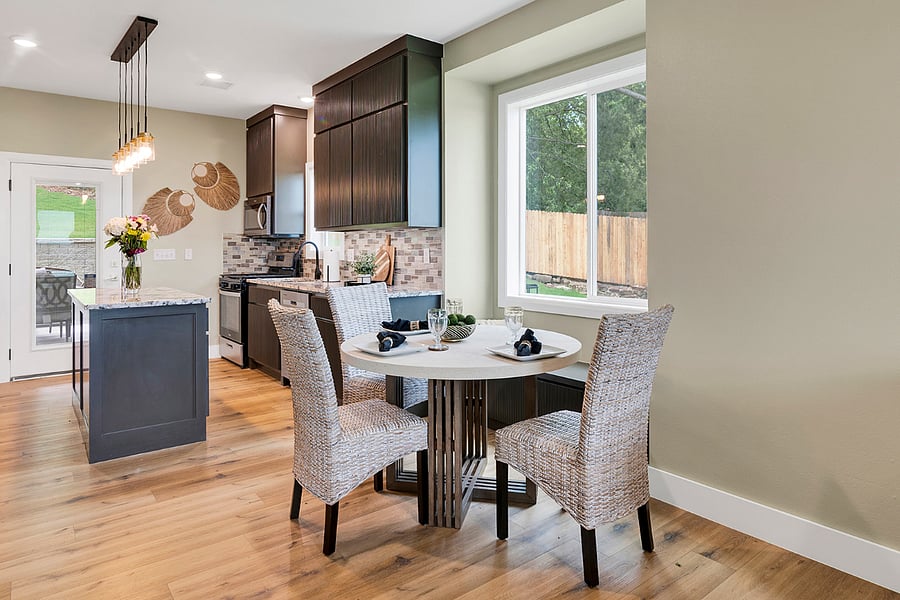 Modern dining area with comfortable chairs and window bench seating, set alongside large windows that enhance natural light and everyday comfort.