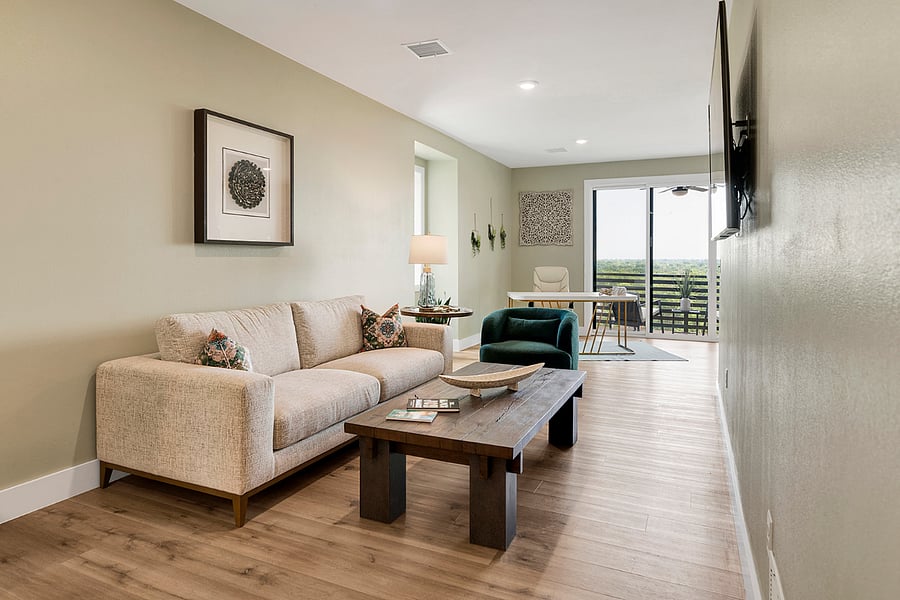 Relaxing living room with a smart TV, plush sofa, swivel club chair, and ambient lightingset against beautiful city views.
