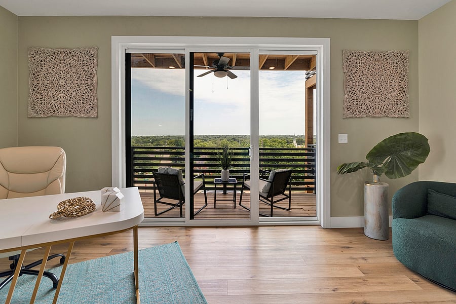A bright work area featuring an oversized desk and executive chair, conveniently located near the balcony for fresh air and inspiration.