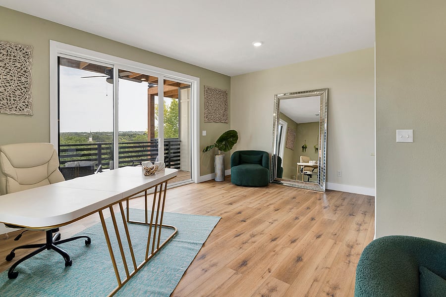 A bright work area featuring an oversized desk and executive chair, conveniently located near the balcony for fresh air and inspiration.