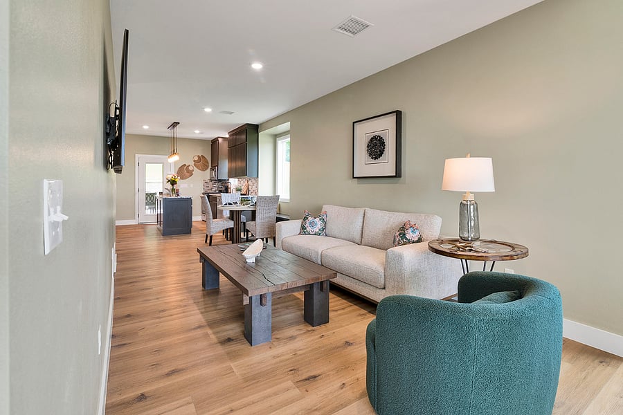 Relaxing living room with a smart TV, plush sofa, swivel club chair, and ambient lightingset against beautiful city views.