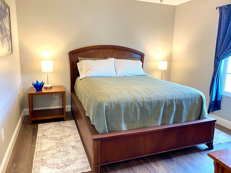 Queen bedroom with pillow-top mattress on stunning vintage bed frame. Closet and dresser behind door.
