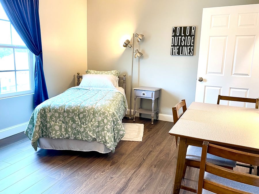 Twin bedroom with closet, dresser, and chairs/table workspace.