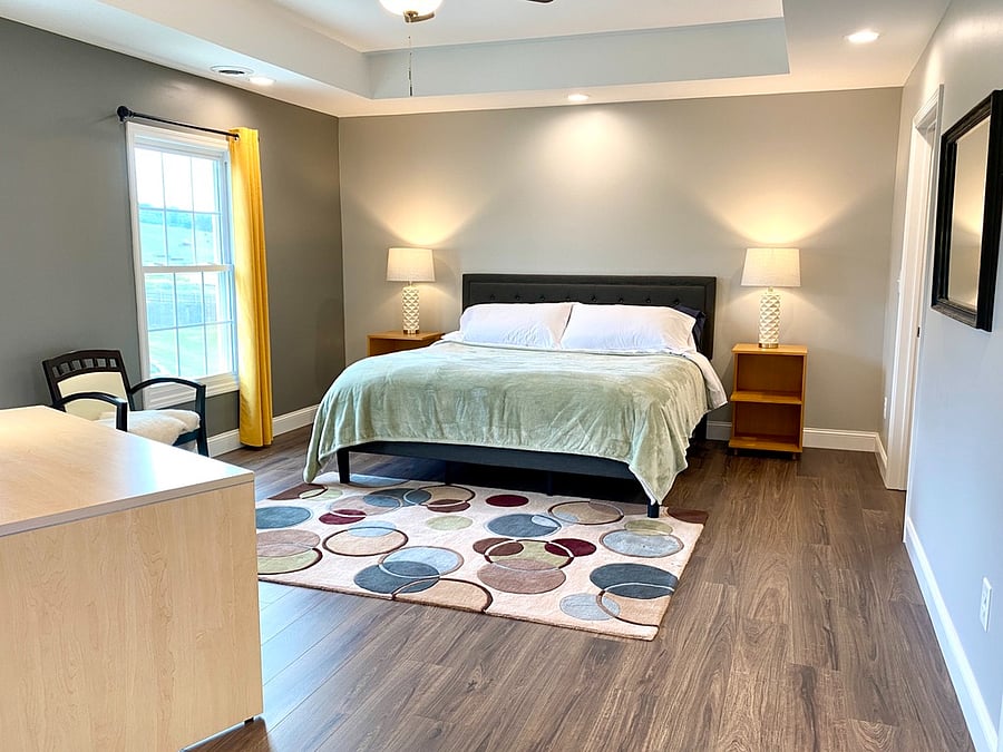 King bedroom with hybrid mattress on platform bed frame, dresser and walk-in closet, trey ceiling with fan.