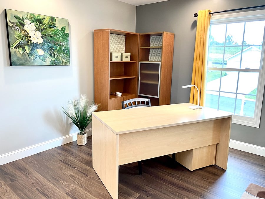 Desk and seating in King bedroom, featuring bookshelves, exterior monitor, and original artwork.