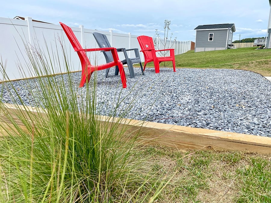 Adirondack chairs in sitting area behind house.