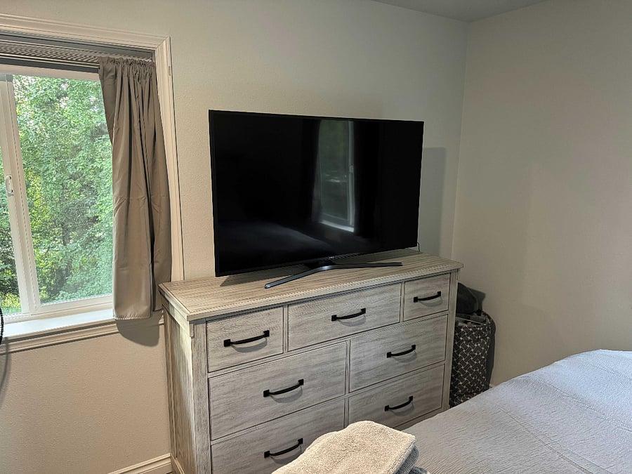 Primary Bedroom Smart TV and dresser with love seat sofa and king bed