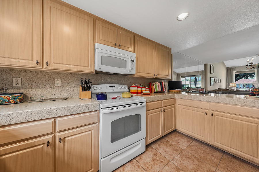 Custom kitchen with quartz counters & backsplash and view through to rear patio.