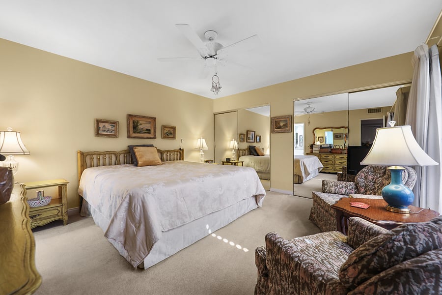 Spacious main bedroom w/ king size bed, sitting area & mirrored wall of closets.