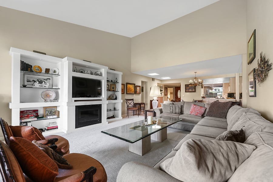 Living room w/ vaulted ceilings & custom wall w/ room heating electric fireplace